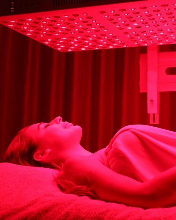 A client resting under the red and near-infrared panel with the panel timer visible at the top of the frame