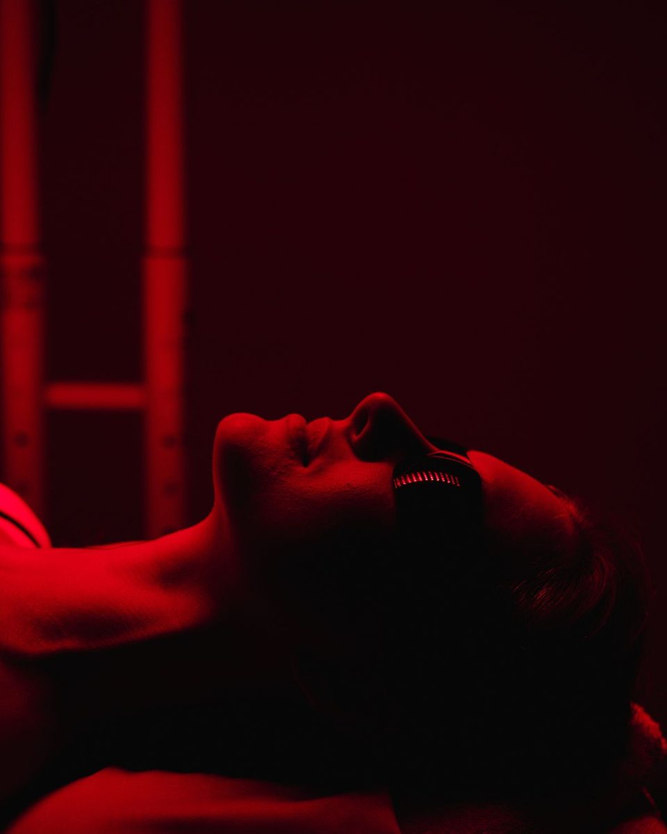 Close-up of a client wearing protective goggles, face lit by the red light panel during a session