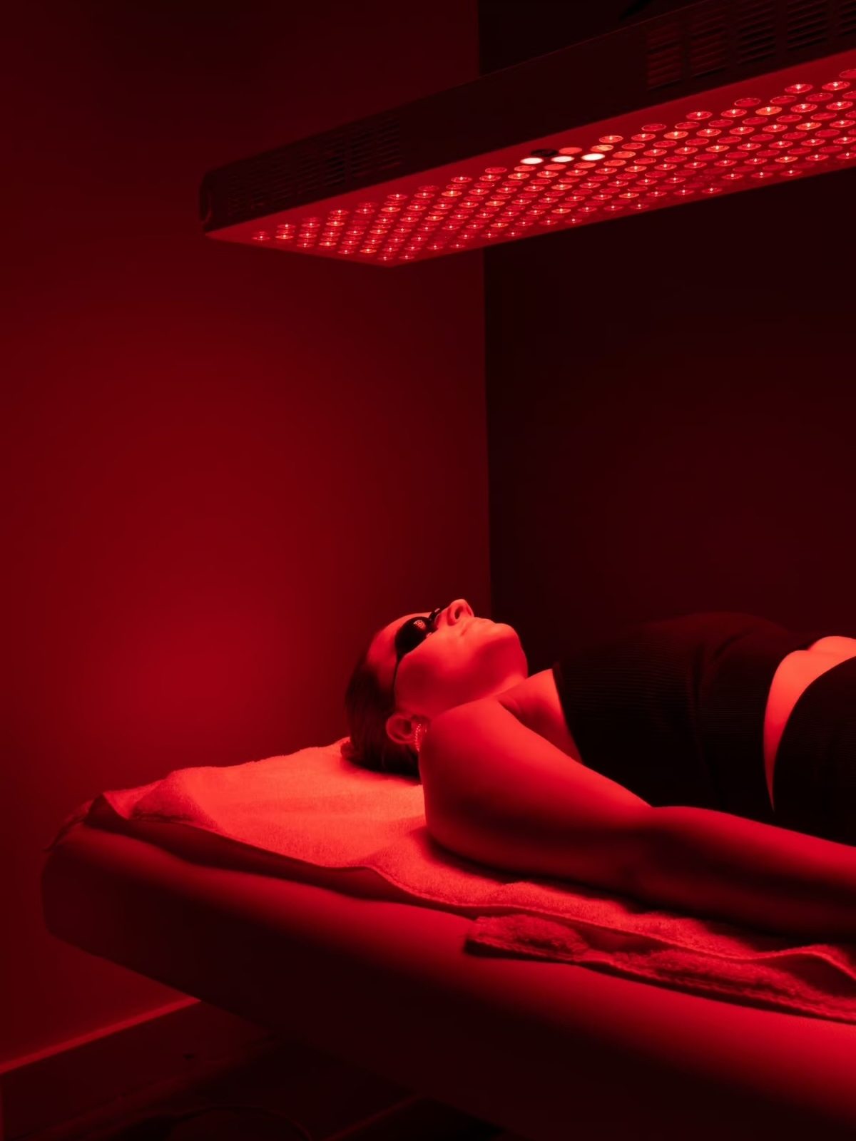 The full-body red and near-infrared panel suspended above a treatment table in the private therapy room at ReVibe Centre in Gander